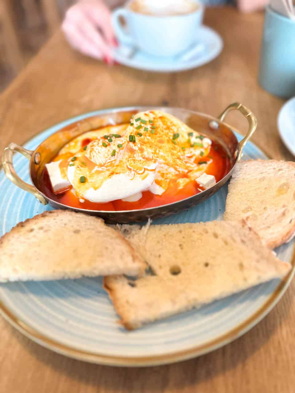 Poached eggs with Sirene cheese in tomato sauce and toast at Izzy's Coffee and Brunch in Sofia, Bulgaria