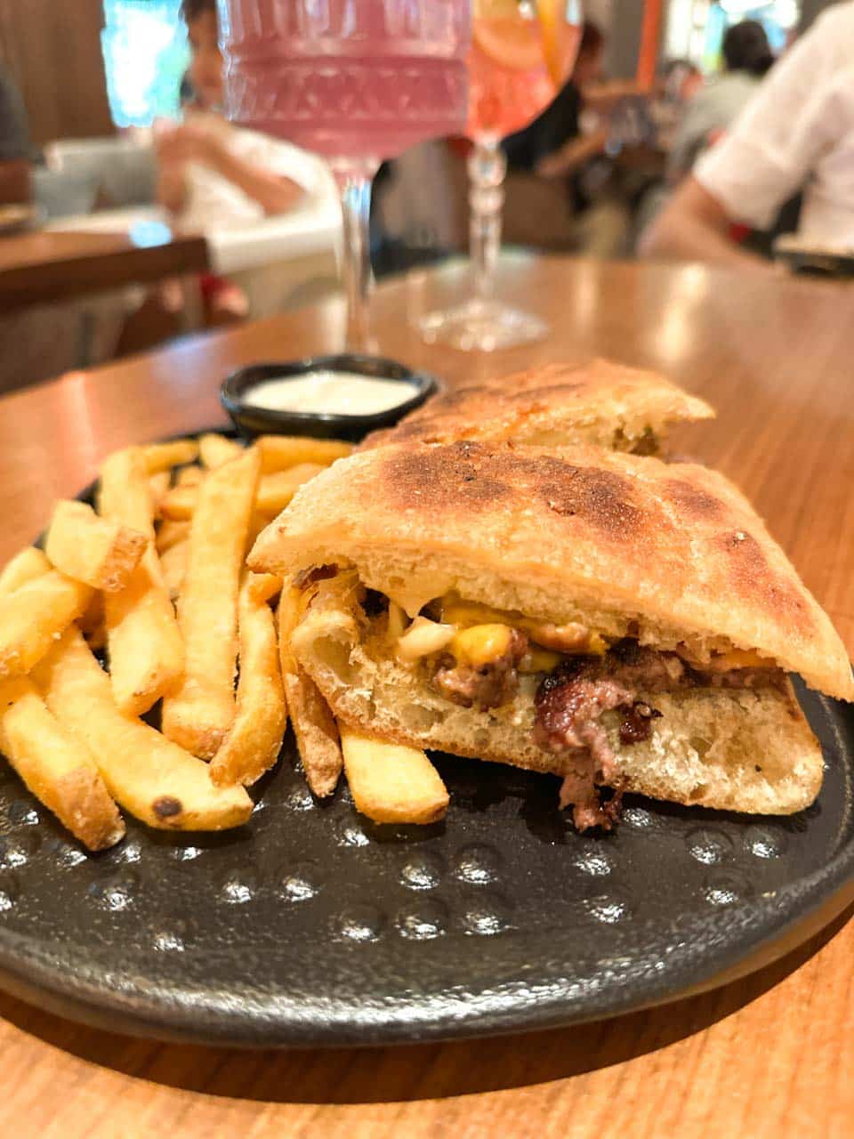 Toasted flatbread sandwich filled with grilled Black Angus beef and melted cheese, served with chips and a creamy dip at Happy Bar & Grill in Sofia