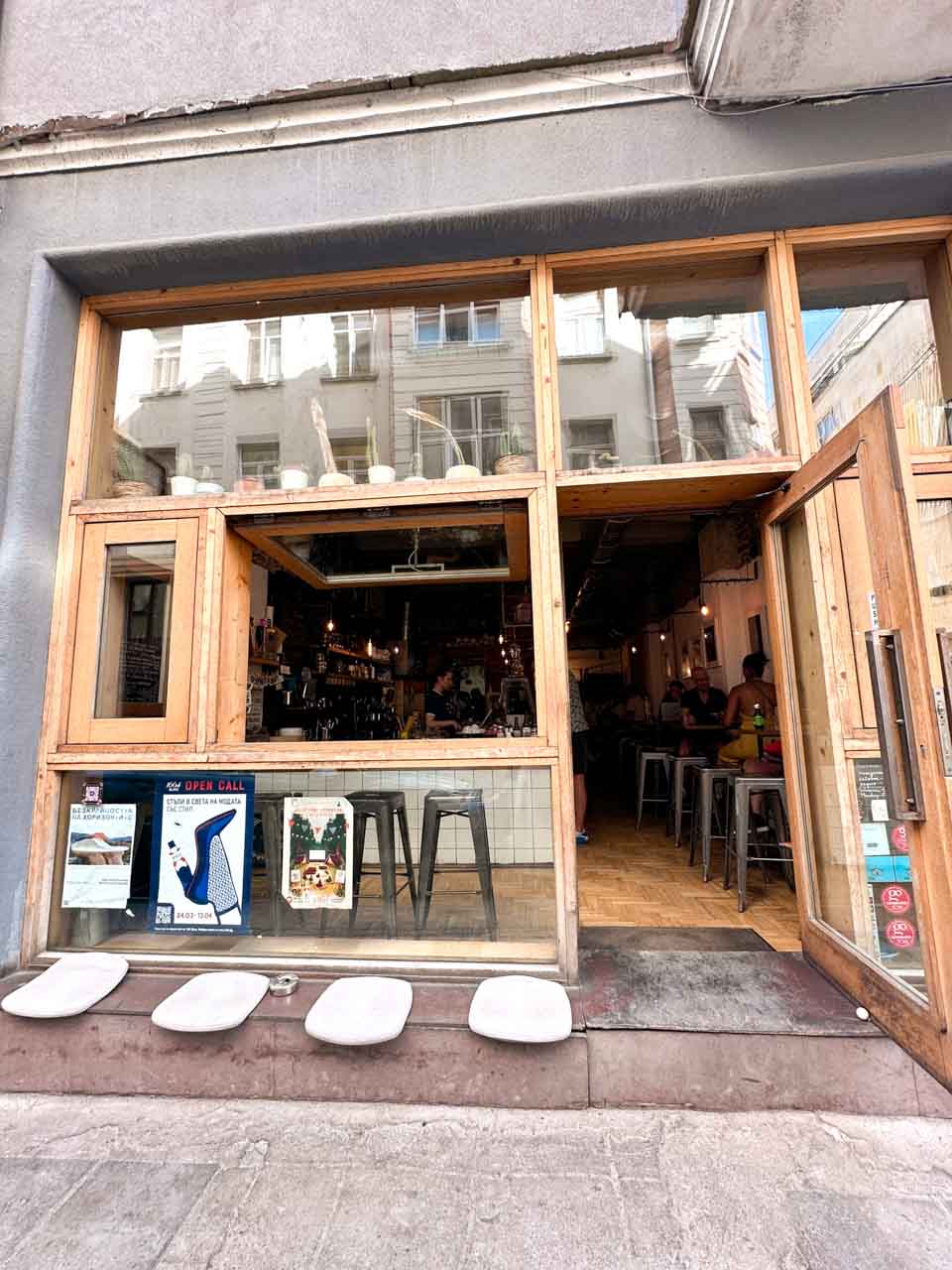 Open-front entrance to Rainbow Factory caf&eacute; in Sofia with large wooden-framed windows and outdoor seating