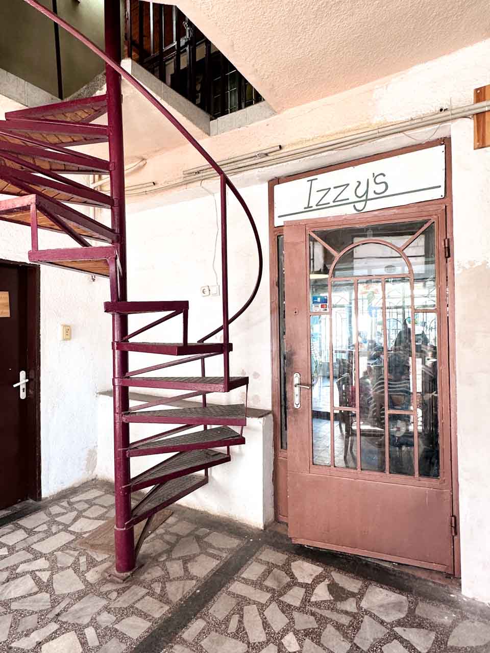 Entrance to Izzy’s Coffee and Brunch in Sofia, next to a burgundy spiral staircase