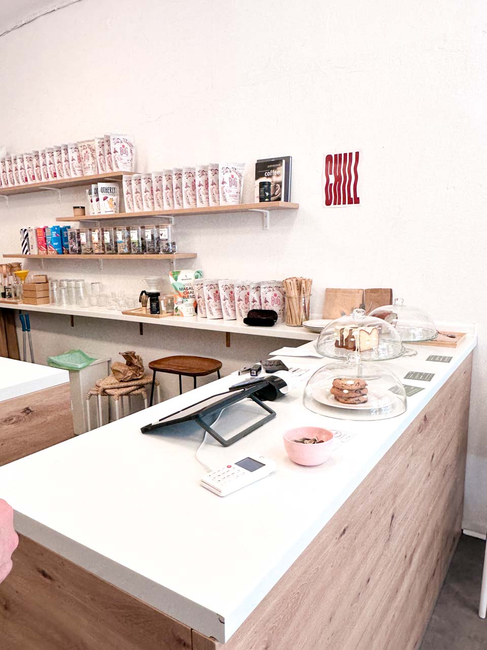 Counter at Bloom Specialty Coffee in Sofia with cakes on display and shelves stocked with coffee and tea