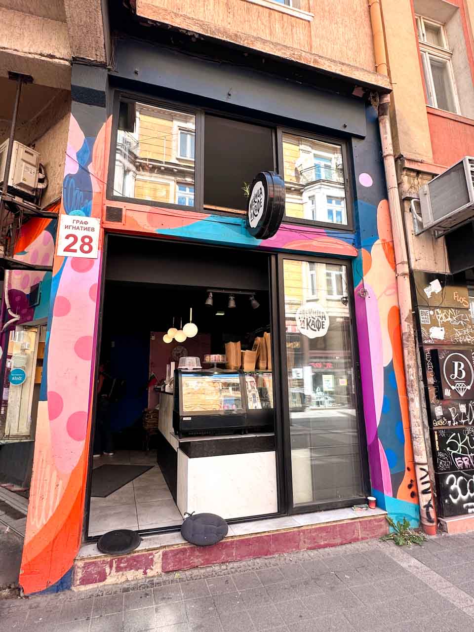 Colourful entrance to Mekitsa and Coffee in Sofia, framed by a bright pink, orange, and blue mural