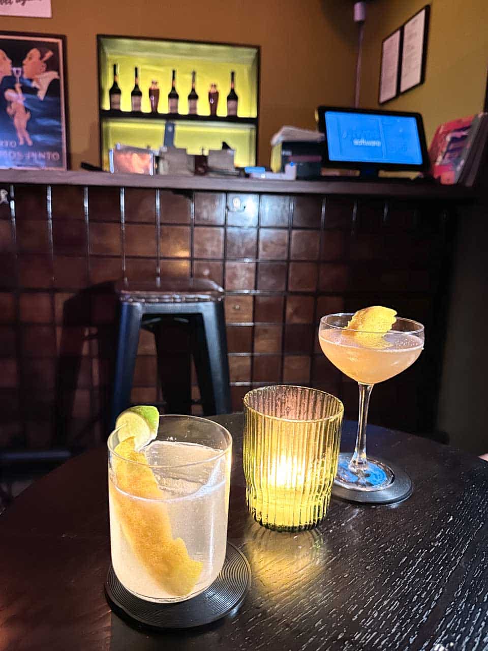 Two cocktails garnished with citrus peel beside a candle inside 5L Speakeasy Bar in Sofia, Bulgaria
